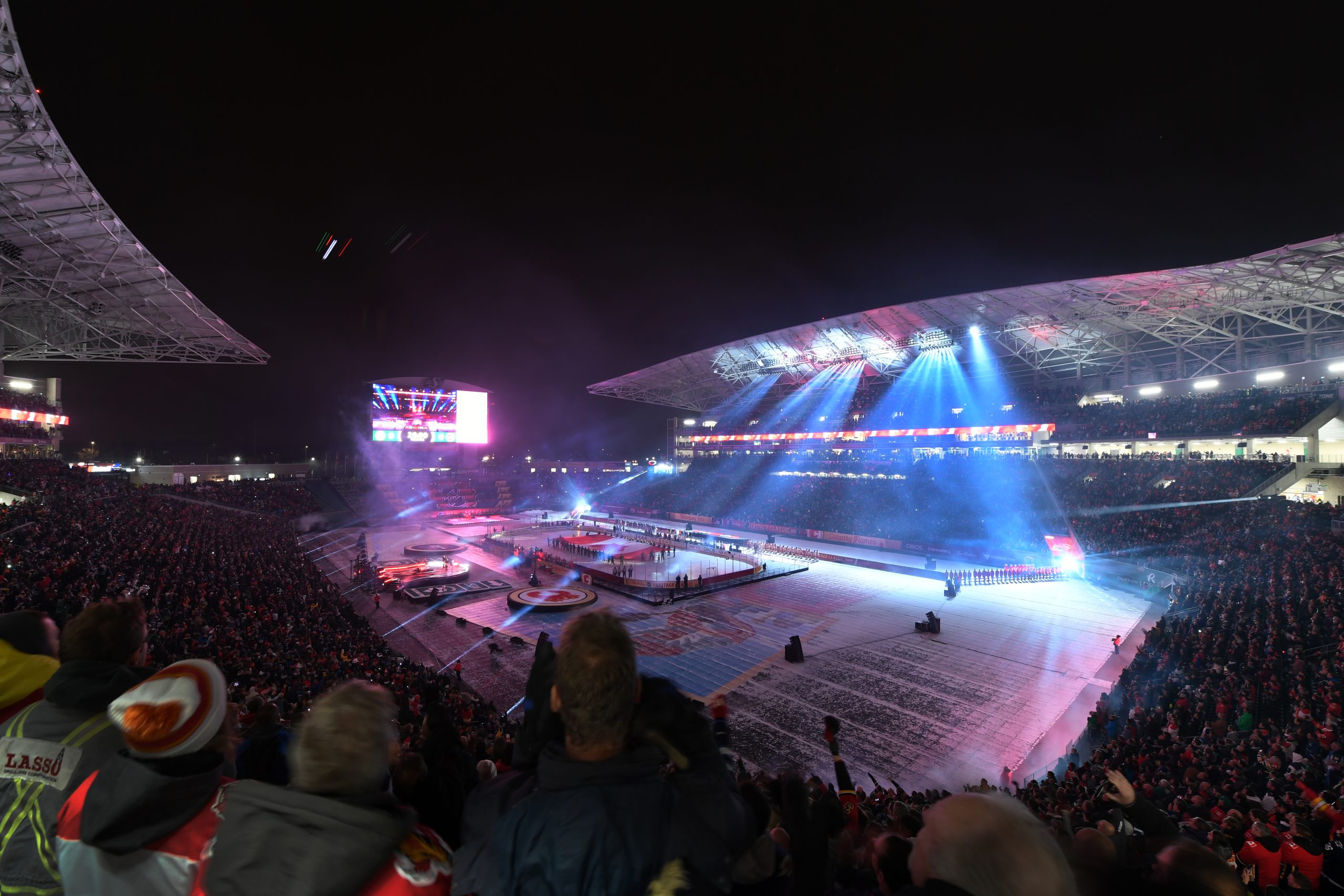 Crowded stadium with illuminated ice rink event.