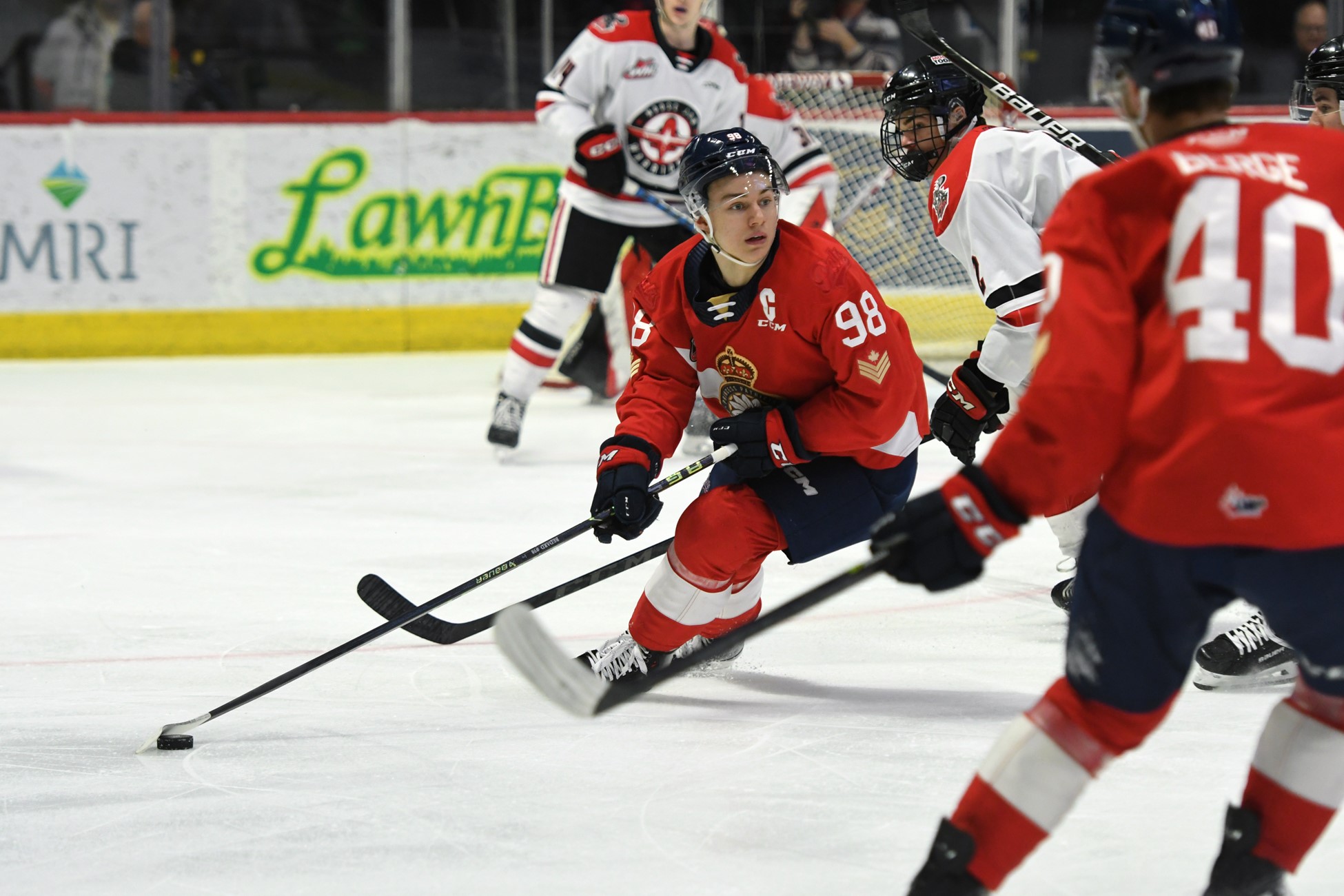 Hockey player in red jersey skating on ice rink.