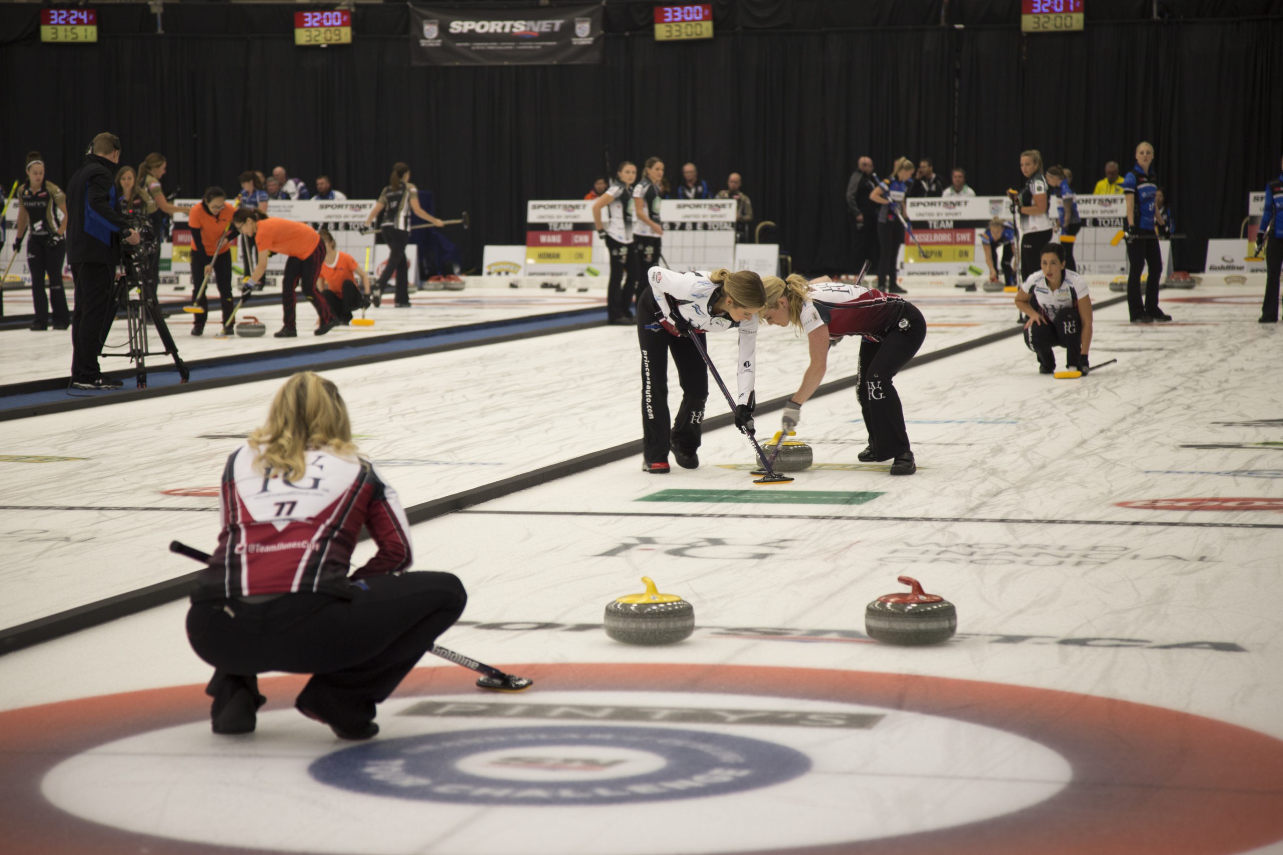 Women's curling match in action on ice rink.