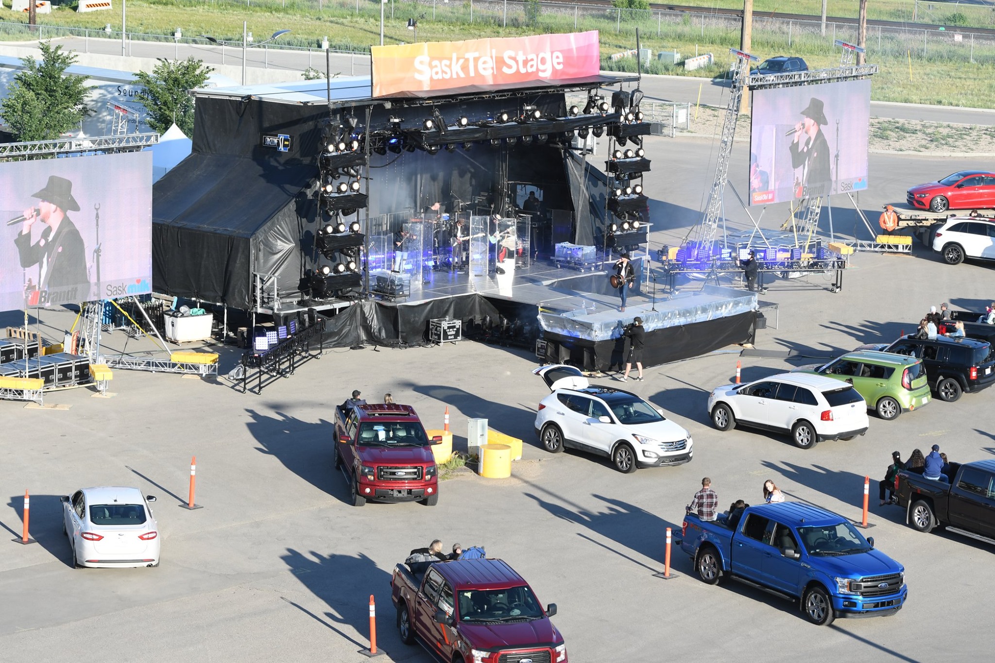 Drive-in concert with stage and audience cars parked.